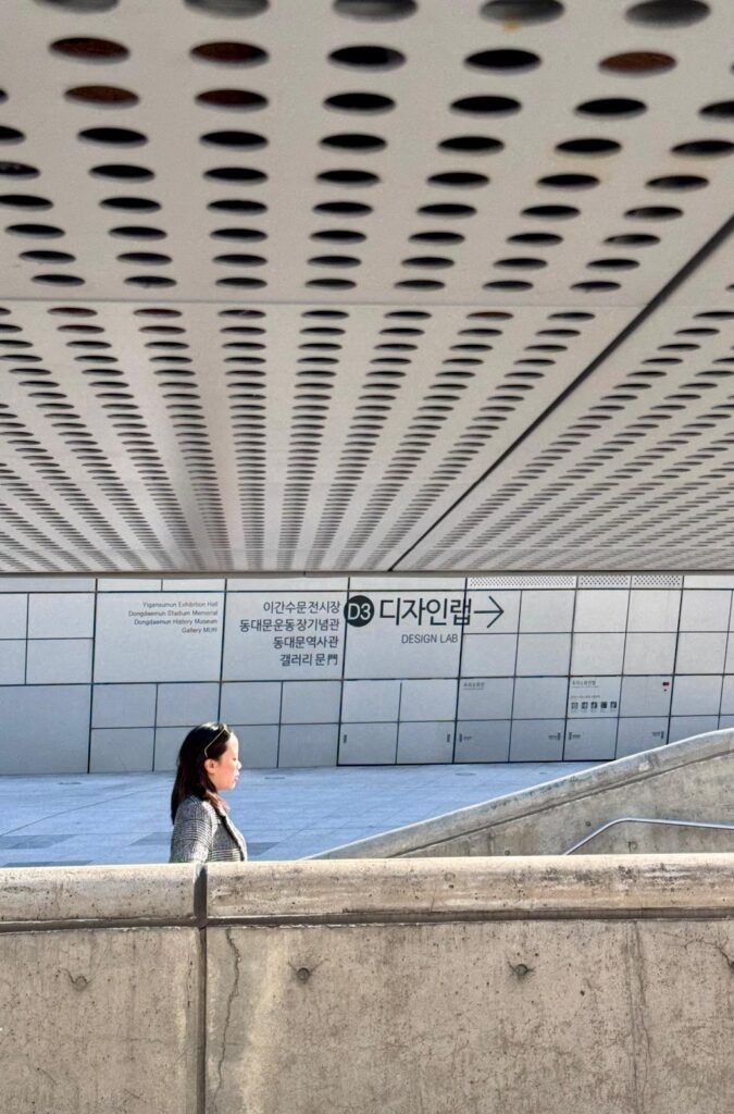 A person standing in front of a buildingDescription automatically generated